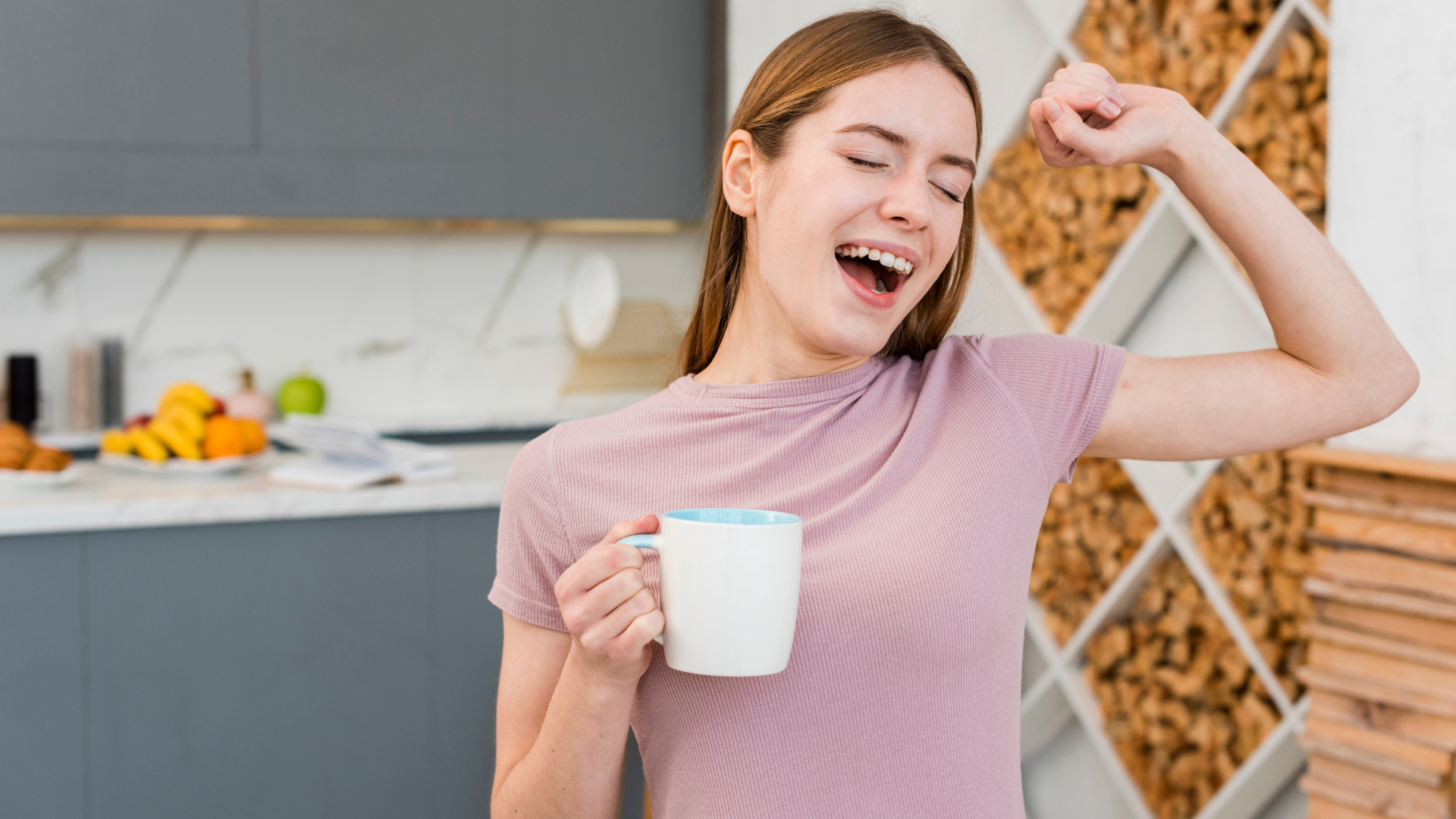 Happy woman stretching and holding a mug of slimming coffee in her hand, standing in a modern kitchen.