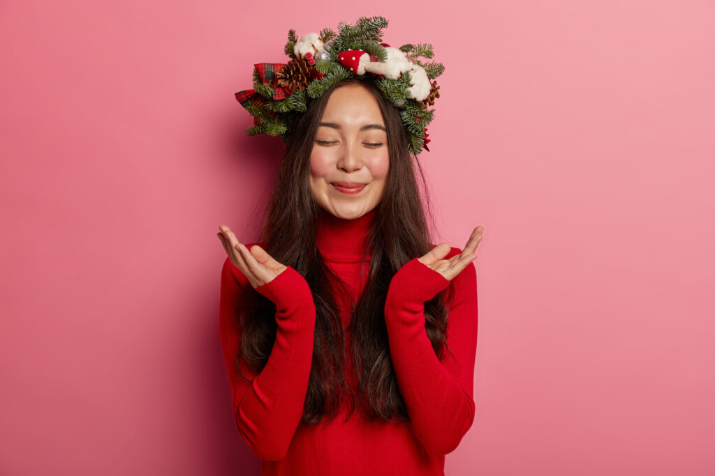 Adorable young lady smiles pleasantly wearing festive wreath on head